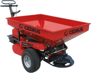 Red hopper-style farm implement on a wheeled frame with a disc spreader underneath.